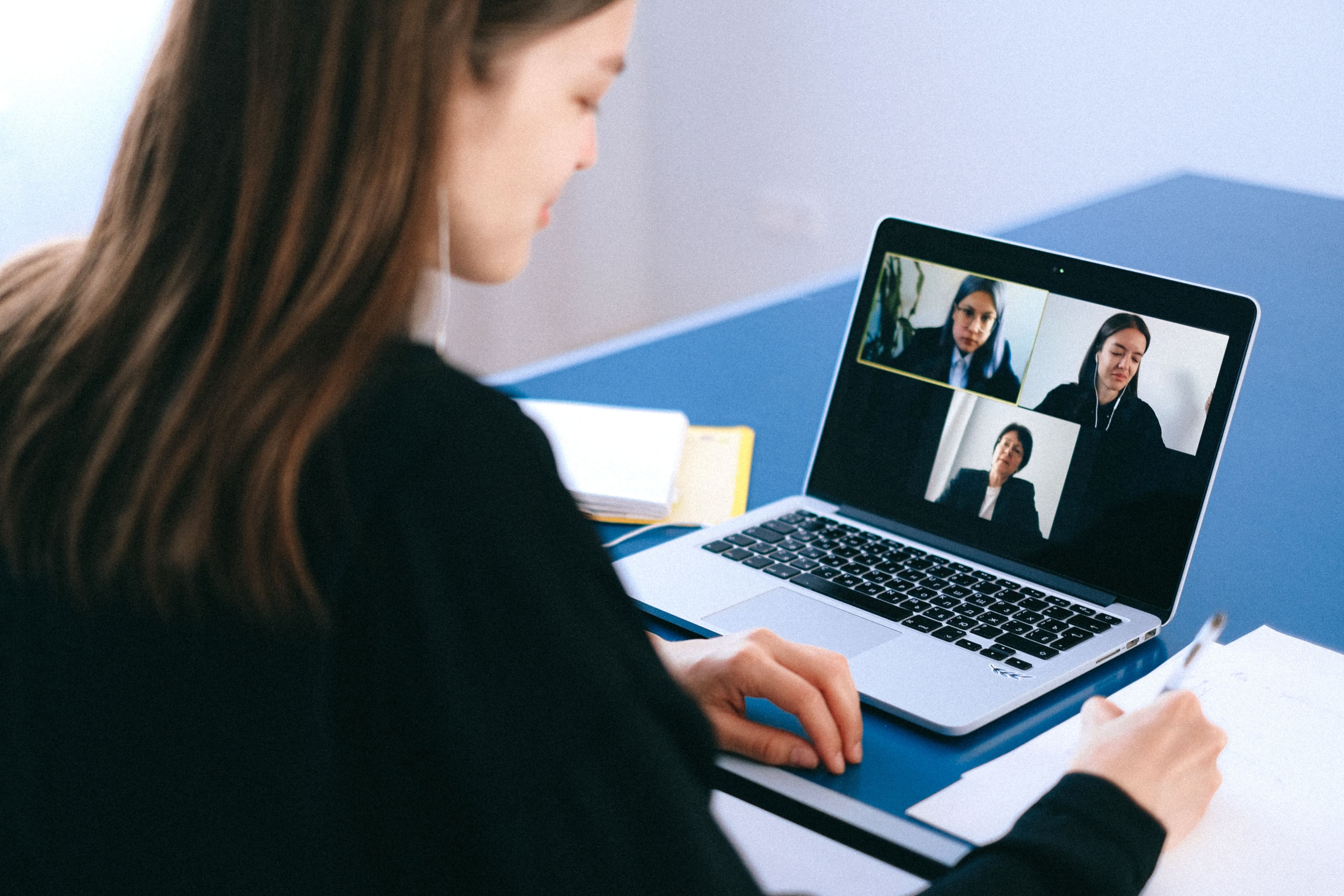 Stock photograph of a woman taking notes beside a video call; the people shown are unrelated to the reported incident.